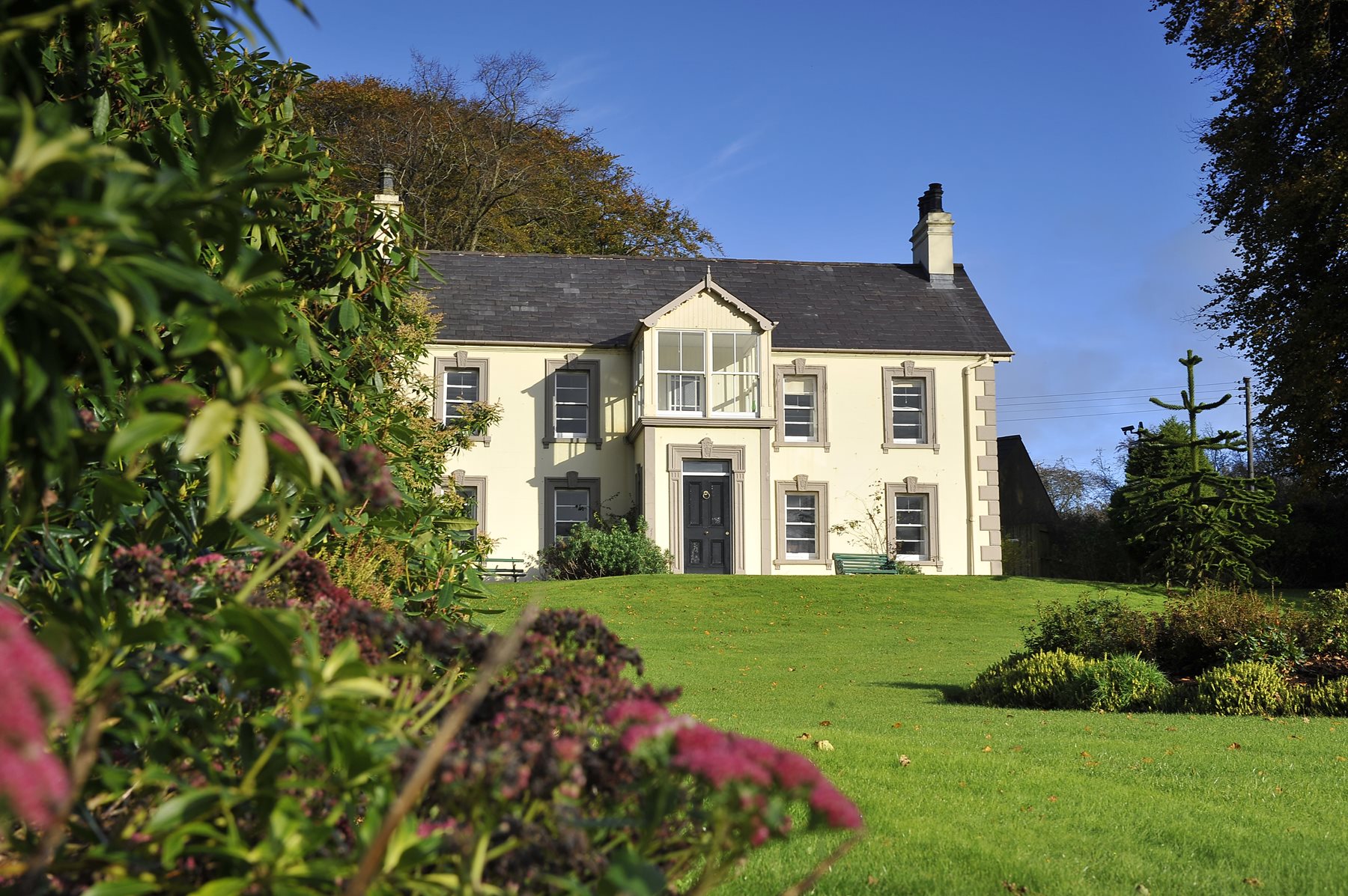 The historic Sentry Hill House, a well-preserved Victorian farm dwelling, surrounded by green lawns in Newtownabbey, Northern Ireland.